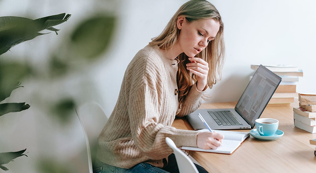 A person reviewing documents while working at a laptop.